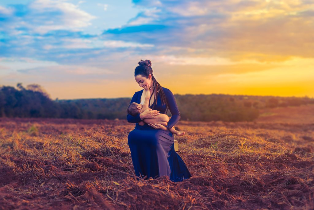 Women feeding her baby sustainable human milk in a field.