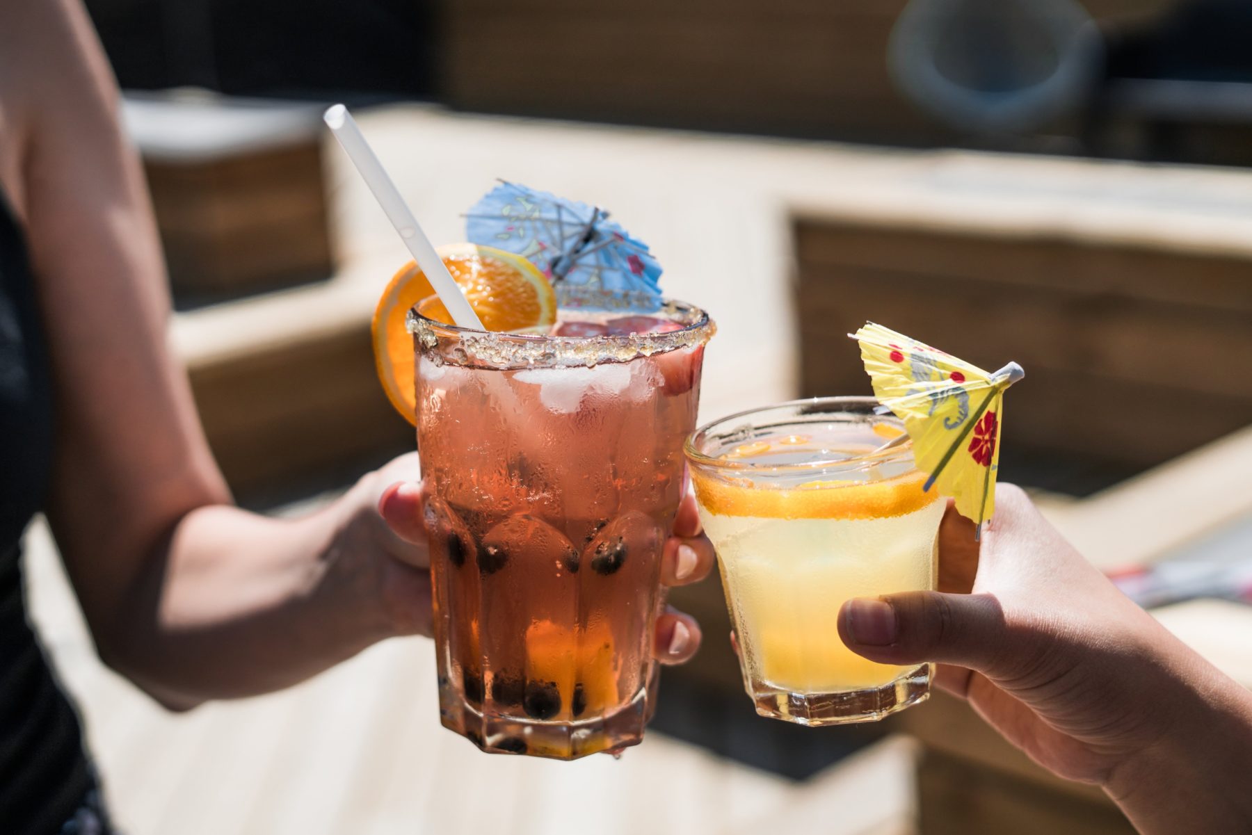 Close-up of two drinks of alcohol with colorful umbrellas. 