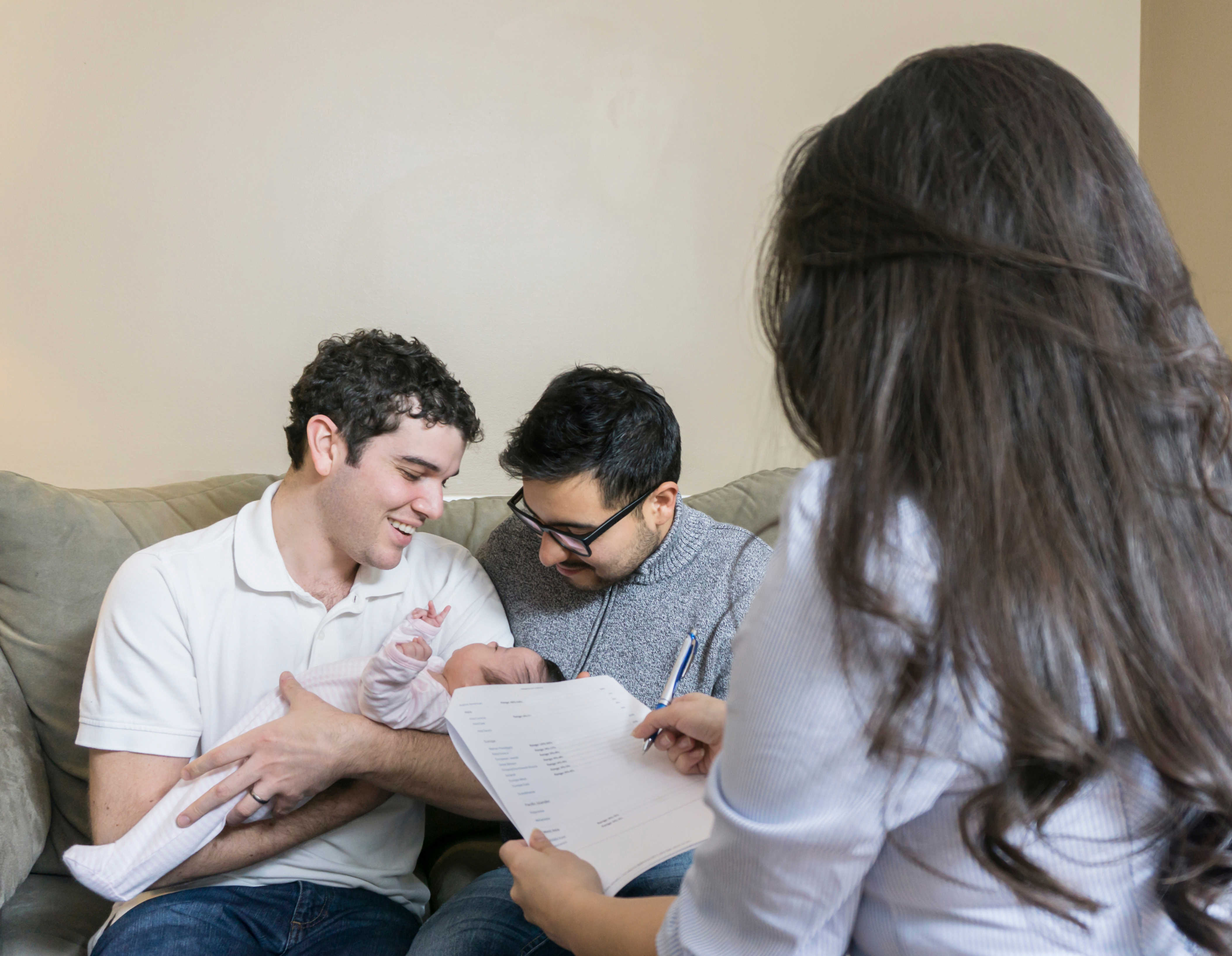 Two dads with newborn and healthcare worker for World Breastfeeding Week 2019