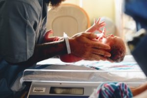 Newborn baby being put on scale to look for newborn weight loss.