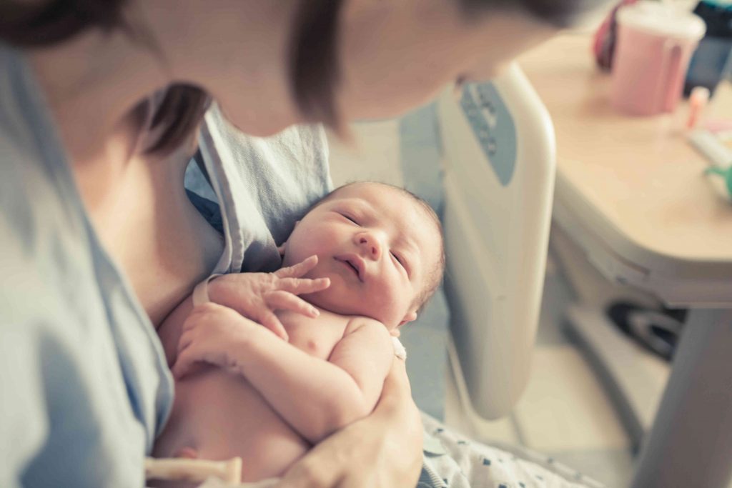 Mother holding newborn baby after breastfeeding