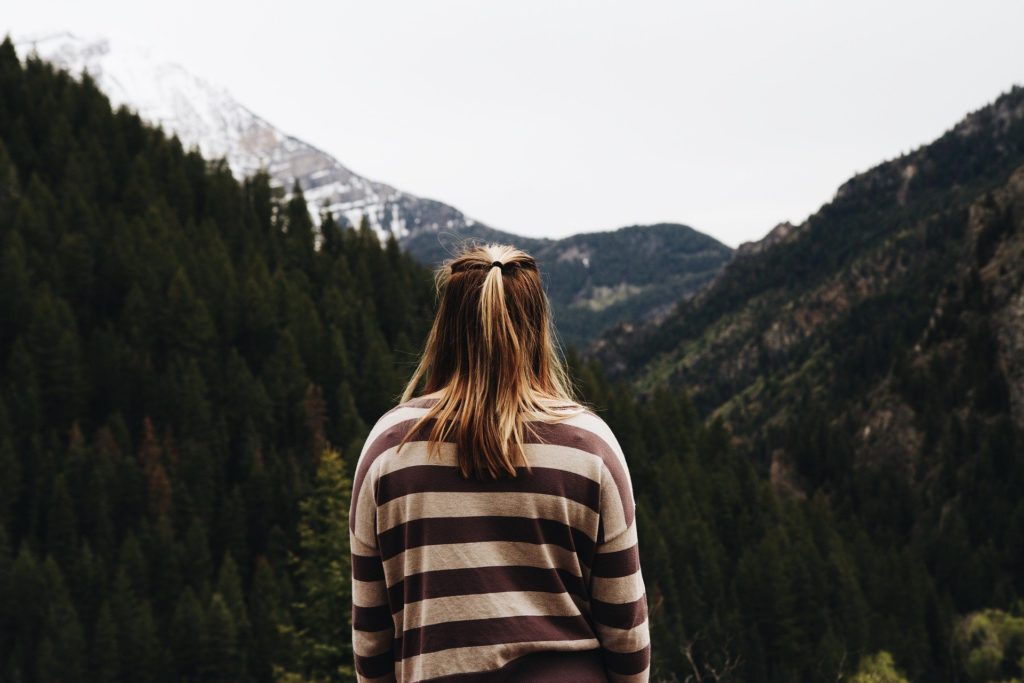 Woman looking at mountains. Why are you not meeting your goals?