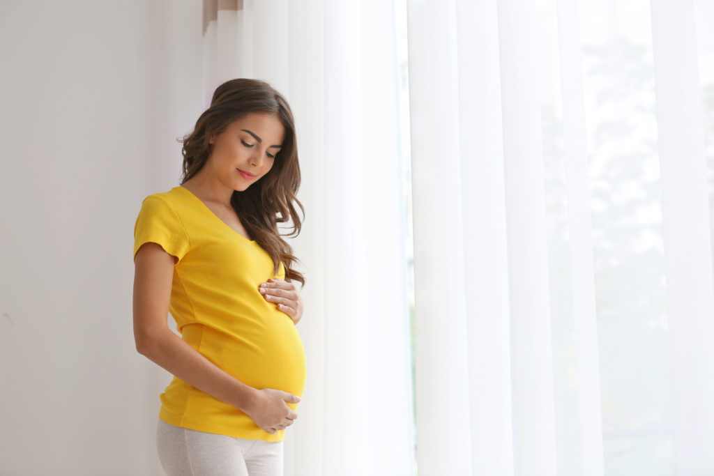 Pregnant brunette in yellow shirt