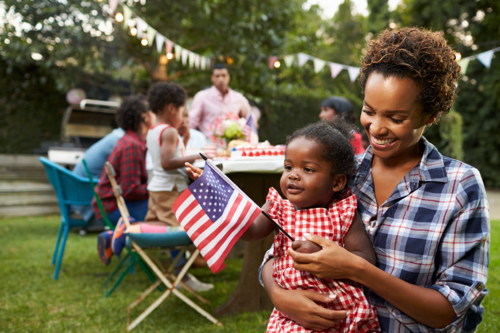 Mother and daughter holding flag at backyard party