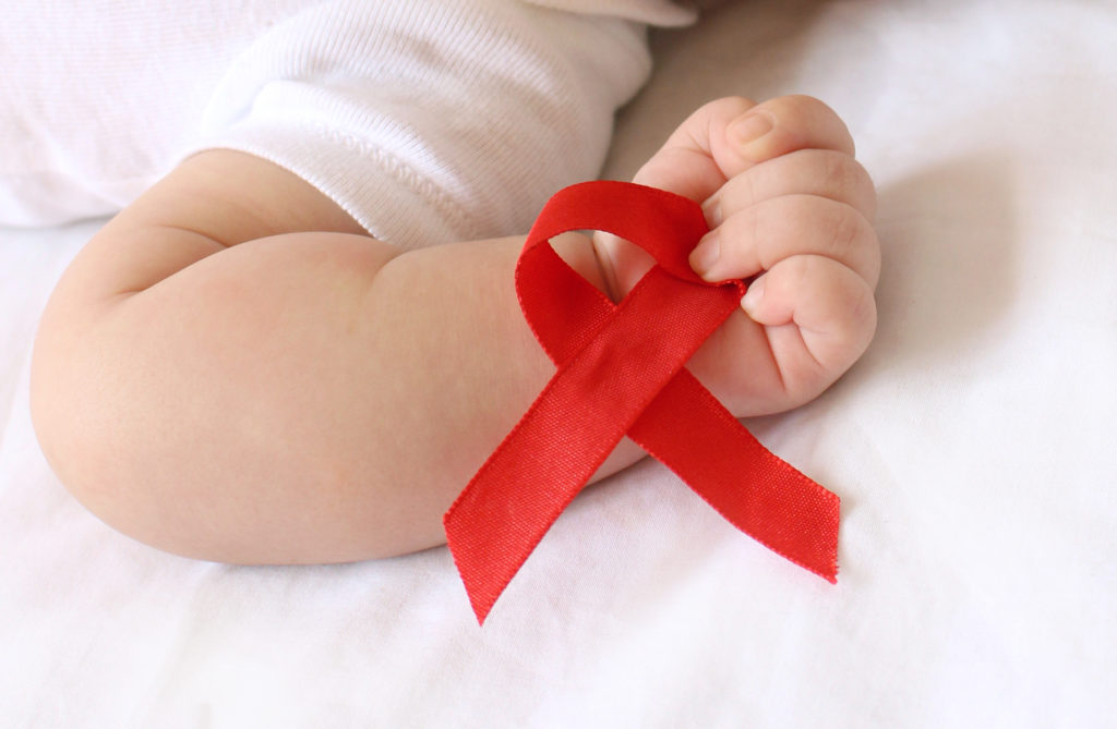 Baby holding red HIV/AIDS ribbon