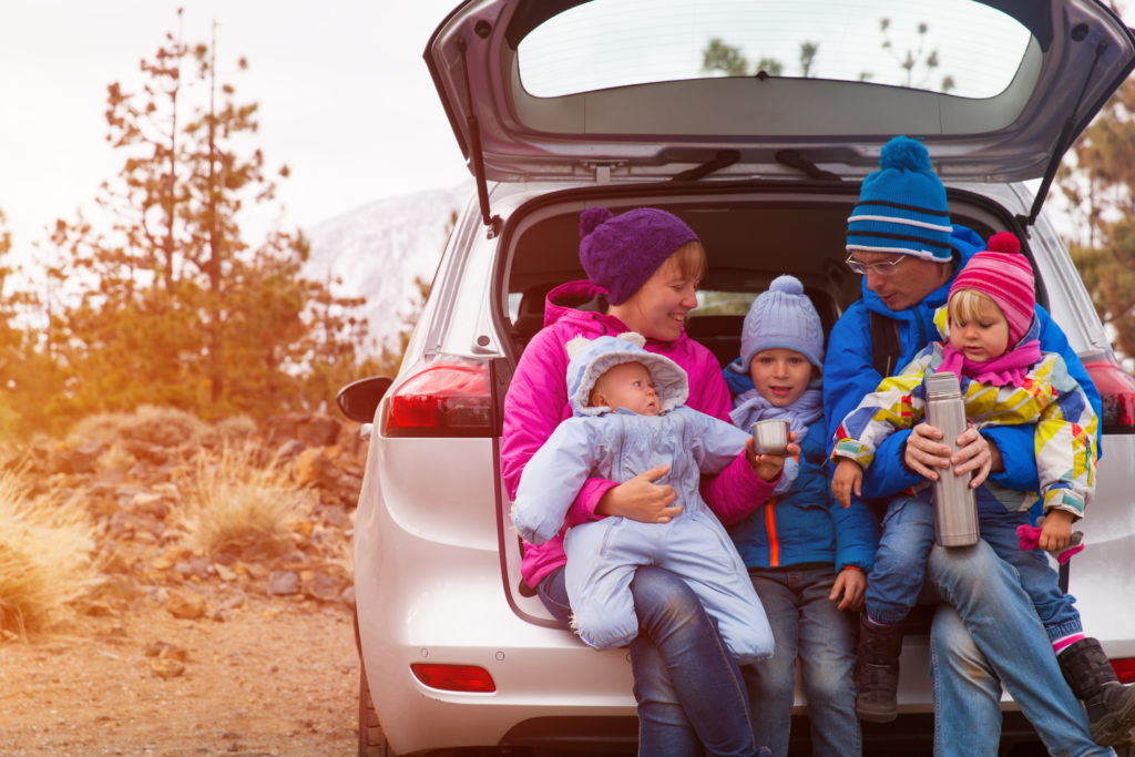 Family in winter clothing traveling in a car with a thermos.