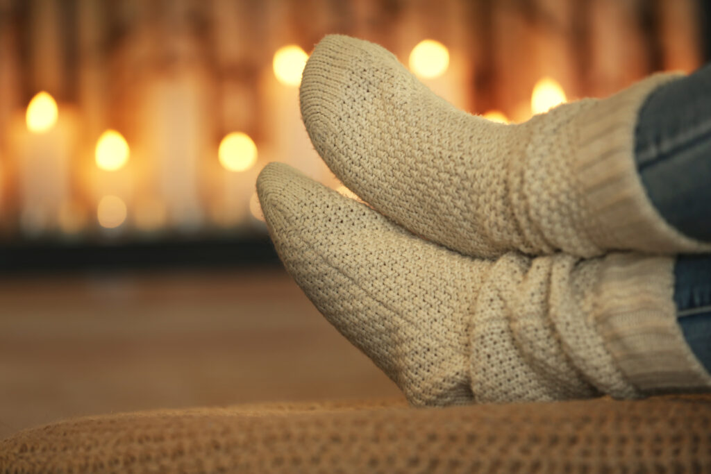 Slipper sock covered feet relaxing in front of candles.