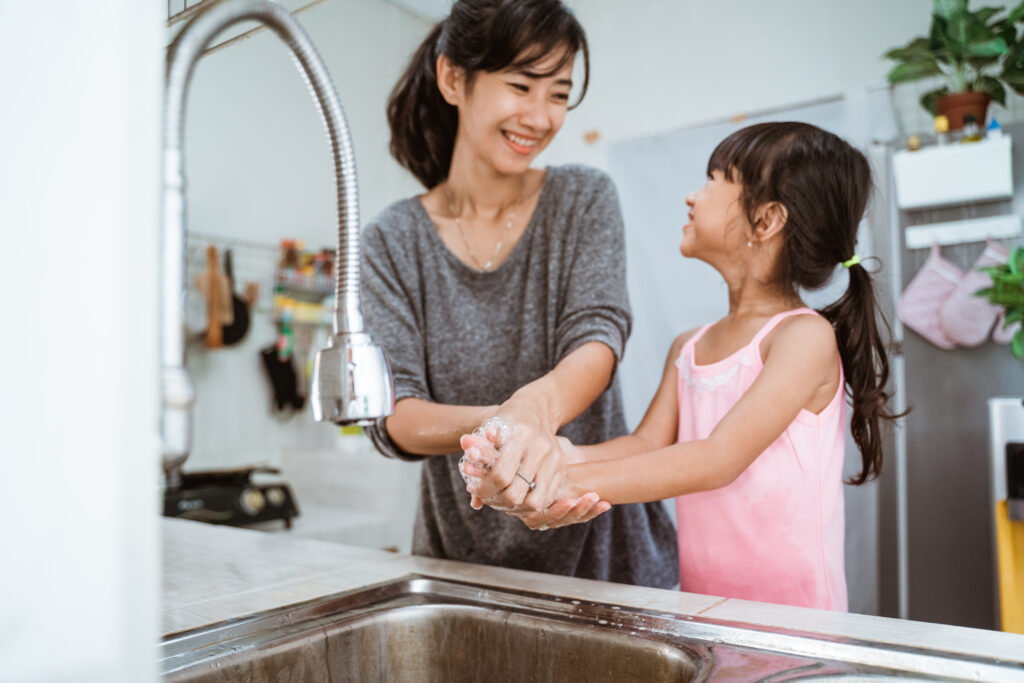 Mom and daughter washing hands at sink