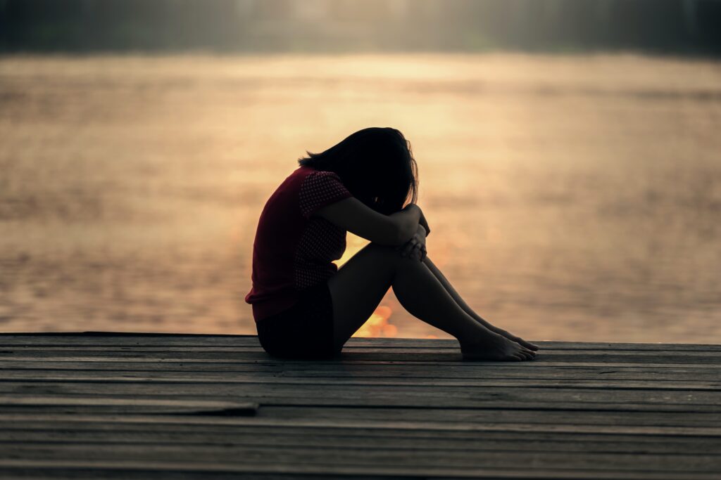 Woman sitting on dock at sunset.