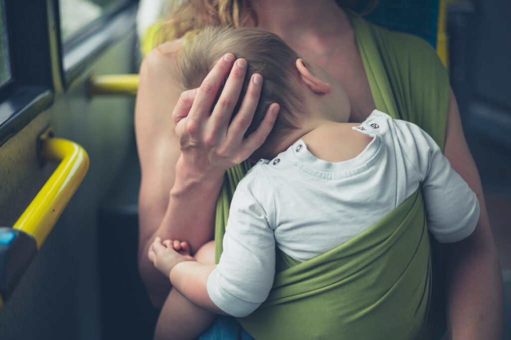 Mother riding a bus while babywearing