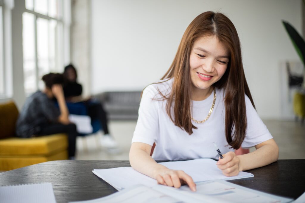 Woman sitting at table with review materials.