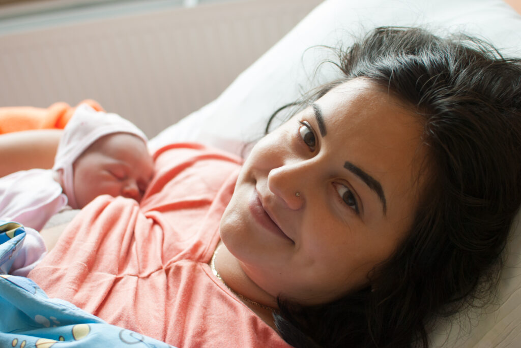 Mom breastfeeding newborn infant in hospital.