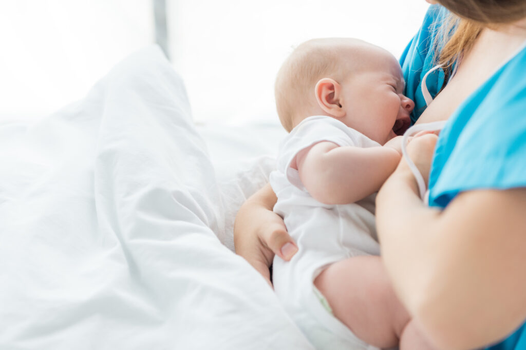 Mom wearing blue with crying baby reluctant to breastfeed. 