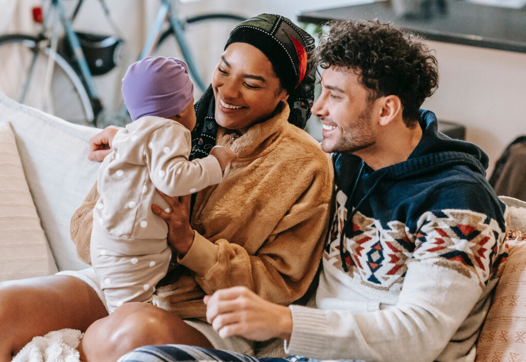 Smiling parents on couch with infant