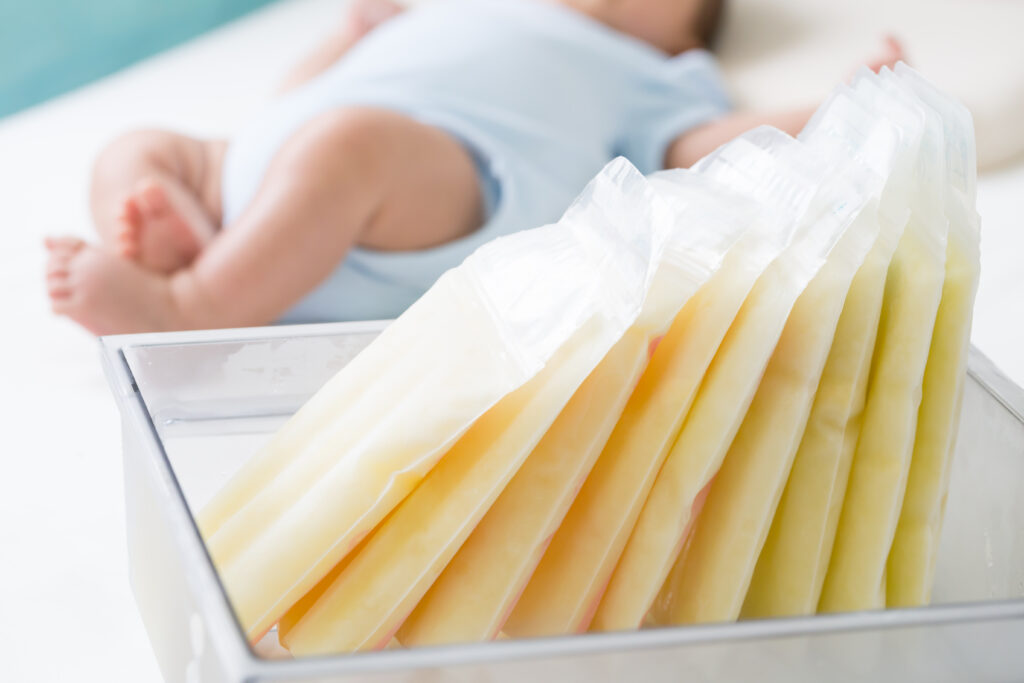 Milk storage bags in a container near an infant.