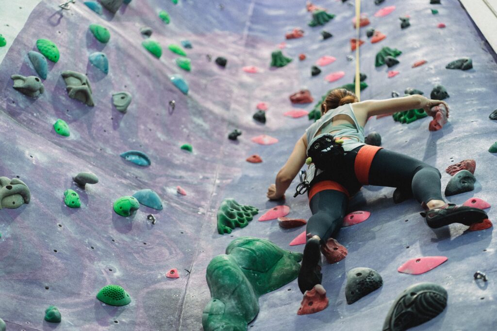 Woman climbing up rock wall obstacle.