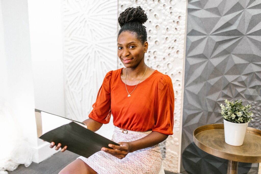 Woman in red shirt holding folder in an office setting.