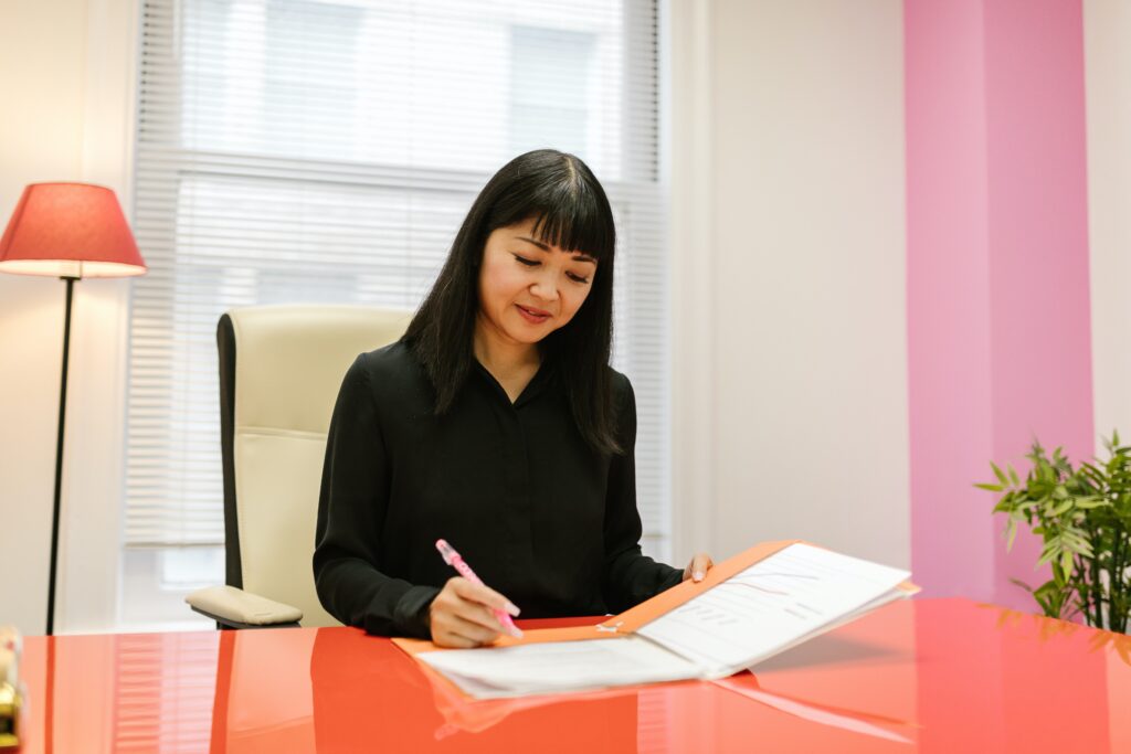 Woman sitting at orange desk completing paperwork.