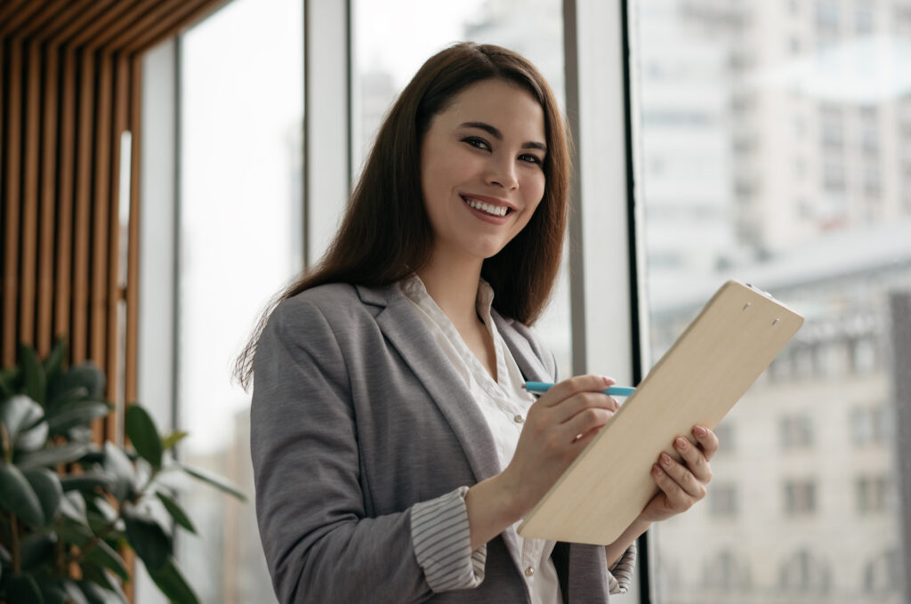 Woman in gray blazer with a clipboard.