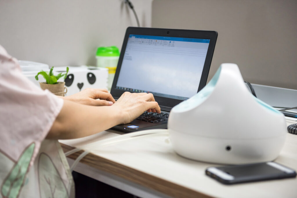 Mom working on computer to save time when pumping milk.