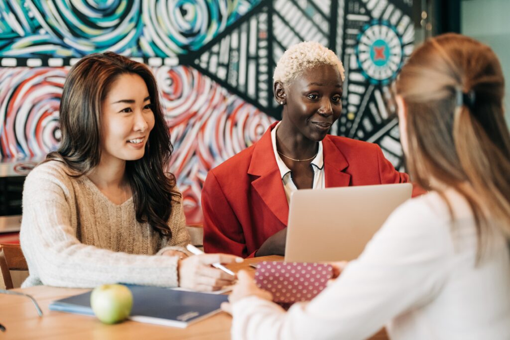 Two women in front of colorful mural being coached in business.