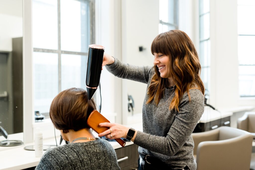 Hair stylist drying client's hair at a beauty salon.