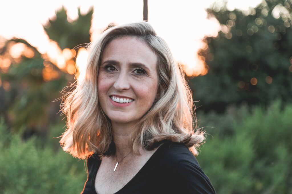 Blonde woman smiling with background lighting.