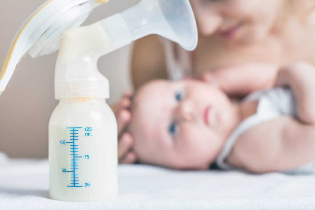 Mom with baby blurred in background with pump bottle in foreground.