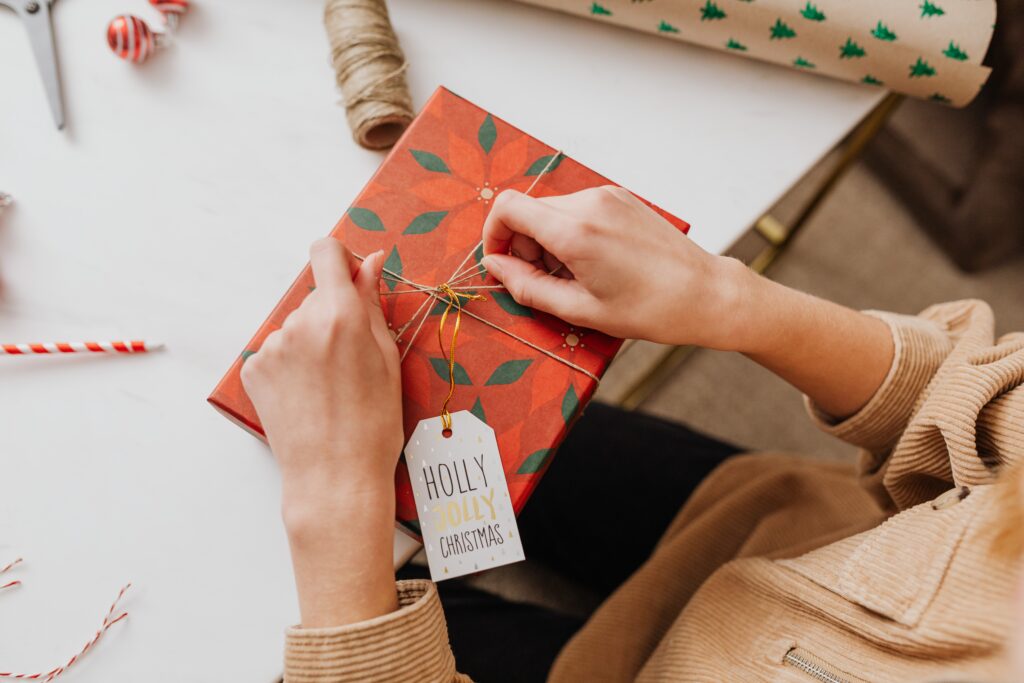 Woman wrapping a gift on a table.