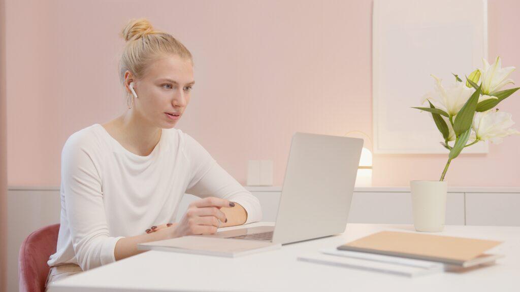 Blonde woman sitting at a laptop computer.