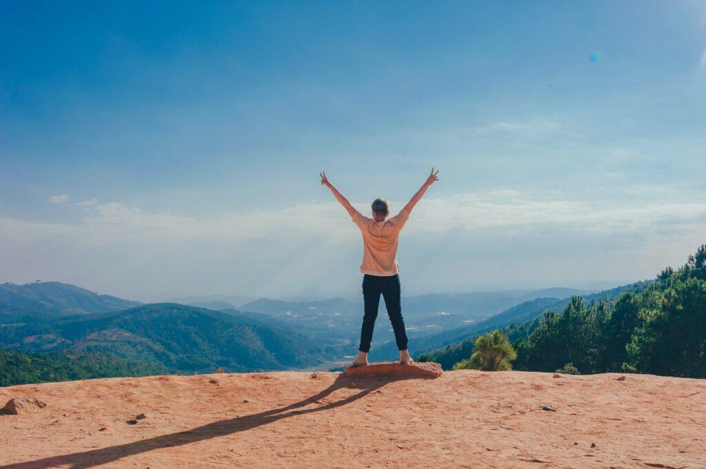 Woman a top a mountain with arms raised.