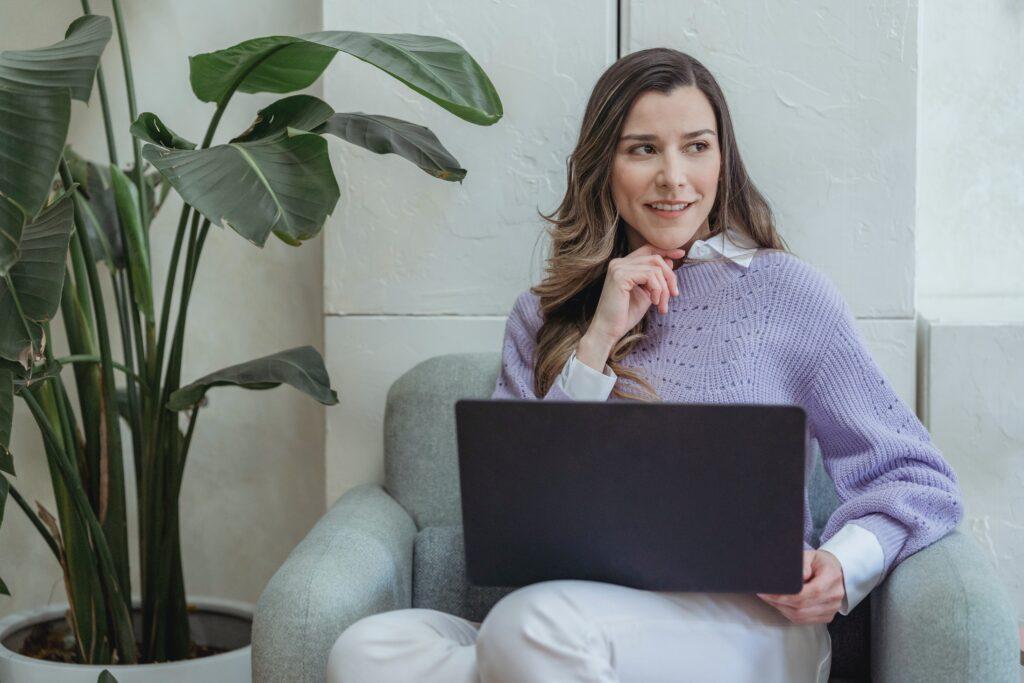 Woman in lavender sweater sitting with a laptop computer. 