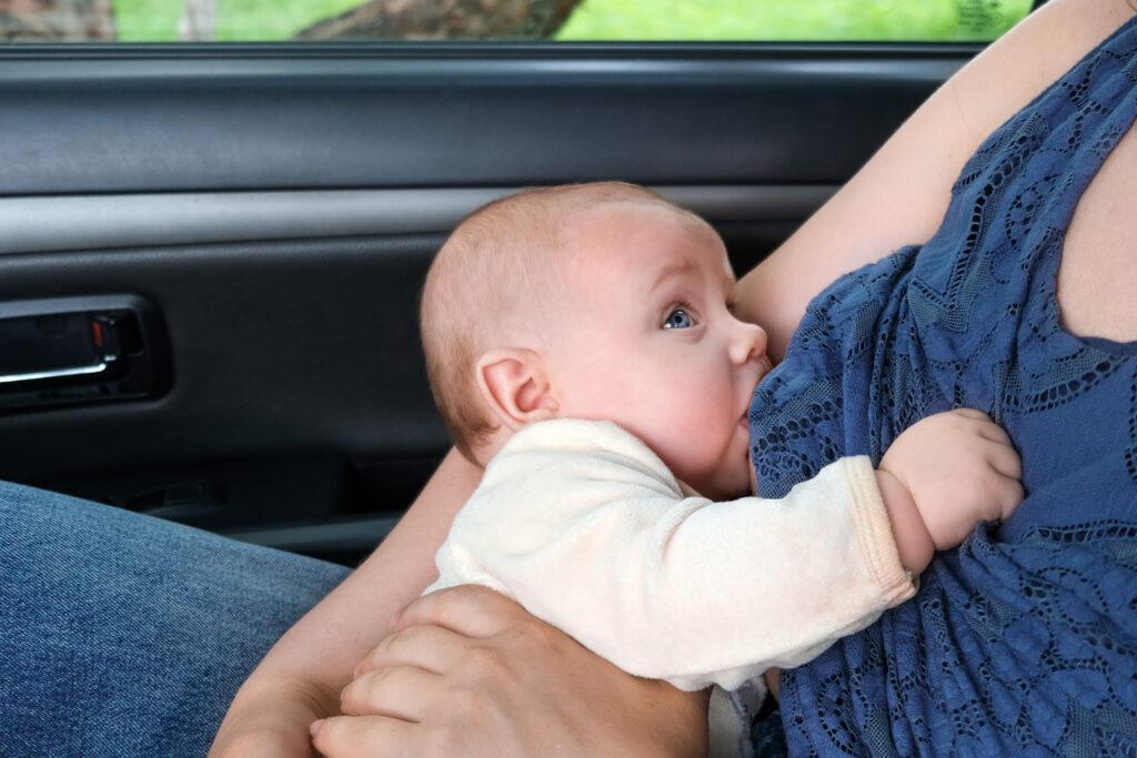 Babby breastfeeding on road trip in stopped car.
