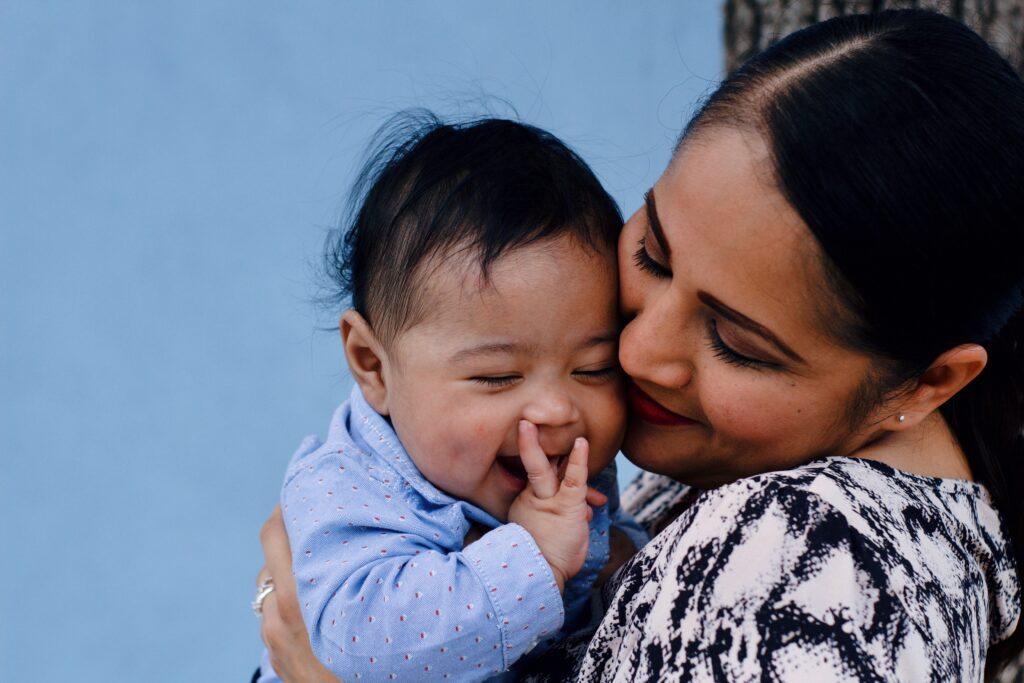 Mother in black and white holding baby in blue shirt. 