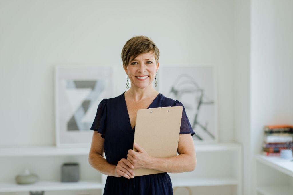 Woman in office holding a clipboard.
