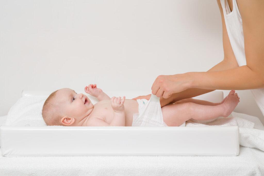 Baby on changing table with diaper being adjusted.