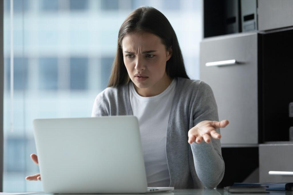 Confused woman sitting in front of a laptop computer. 