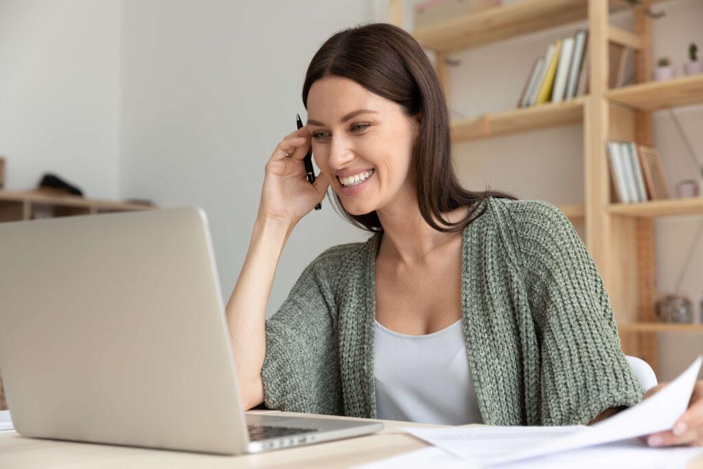 Woman wearing green sweater studying on a laptop computer.