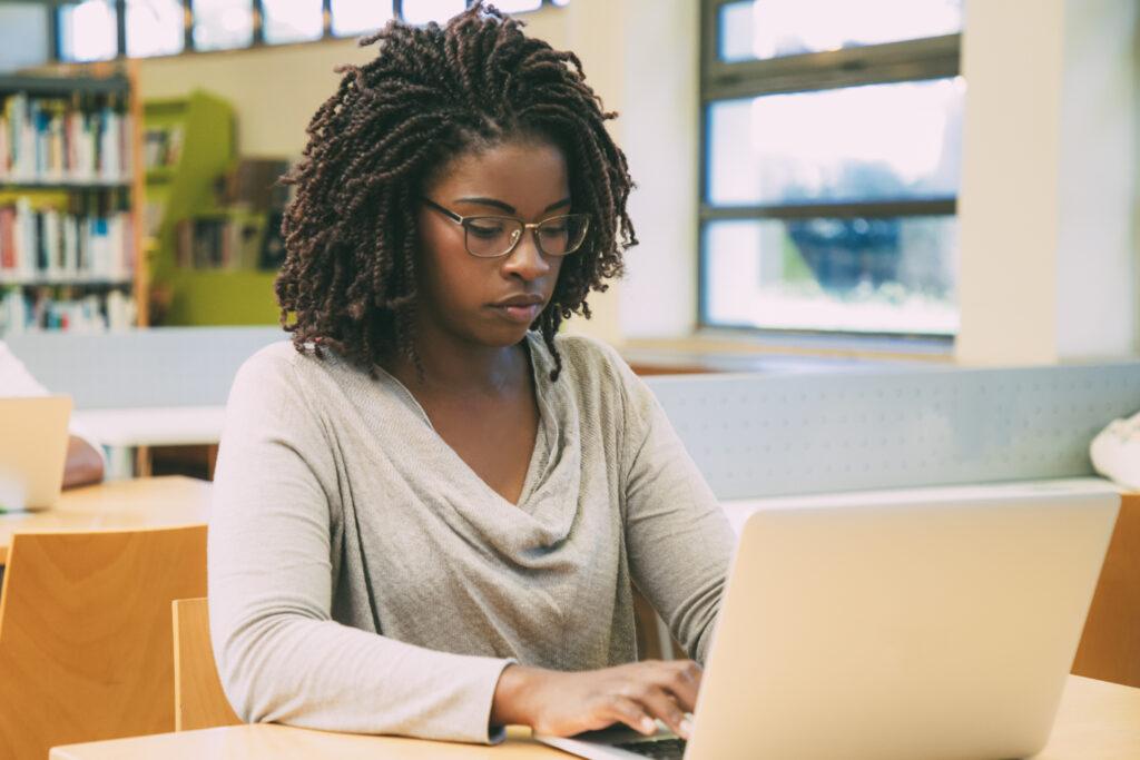 Black woman sitting at a laptop computer studying.