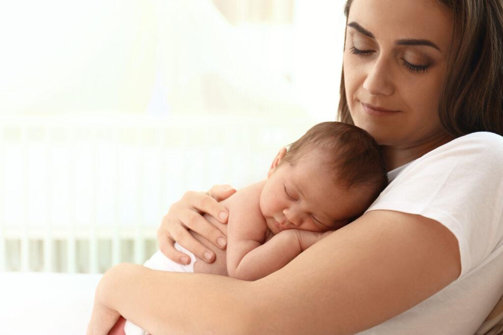 Brunette mother holding newborn baby in diaper.