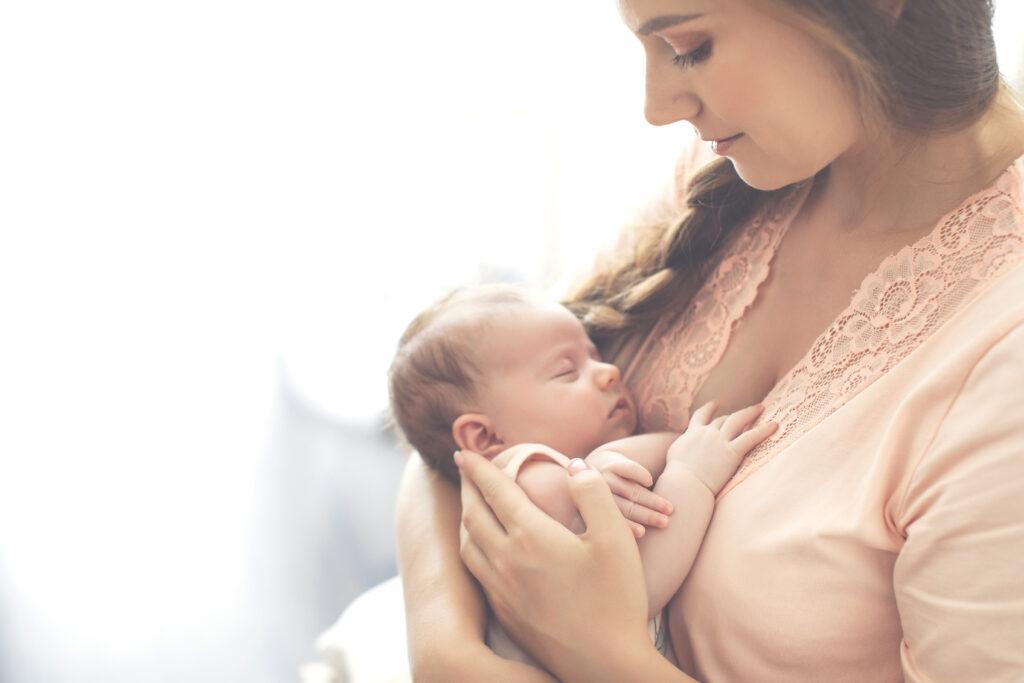 Mom in peach blouse holding newborn baby.