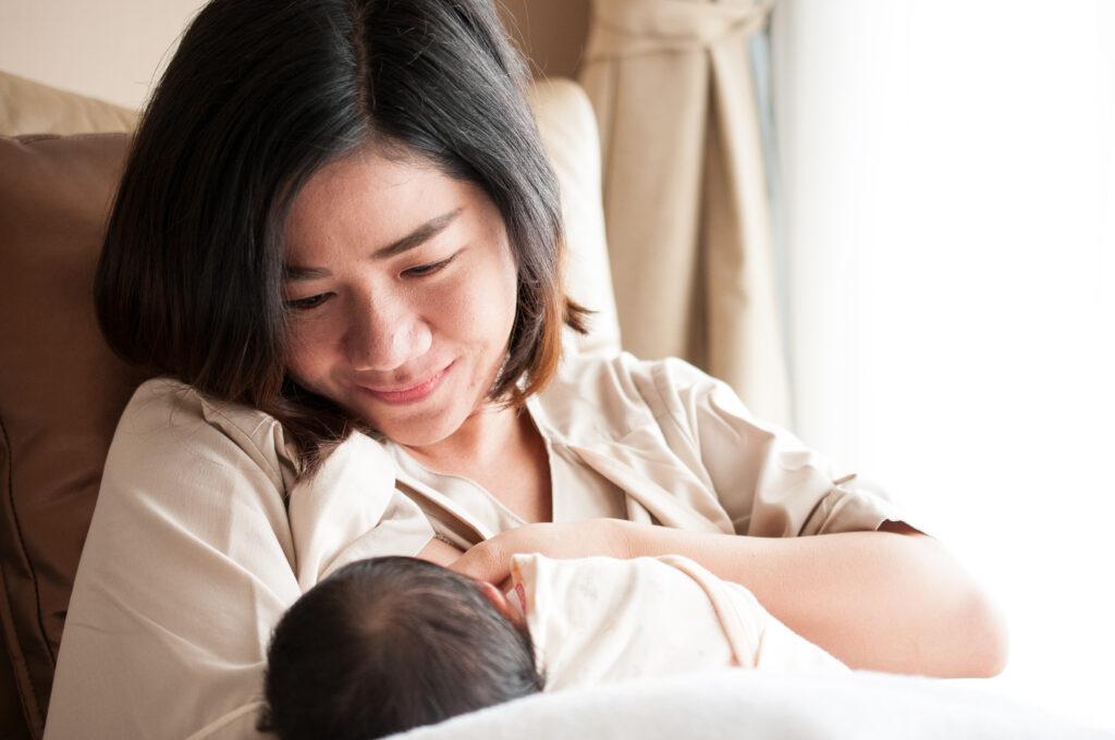 Asian mother breastfeeding newborn baby.