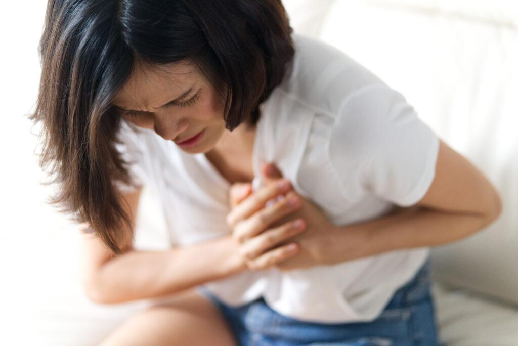 Woman in white shirt holding breast in pain from pathologic engorgement. 