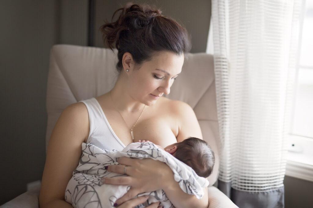 Brunette mother breastfeeding small infant.