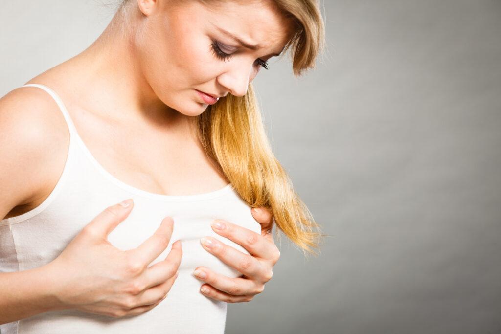 Blonde woman holding her breasts with confused expression wondering about physiologic engorgement.