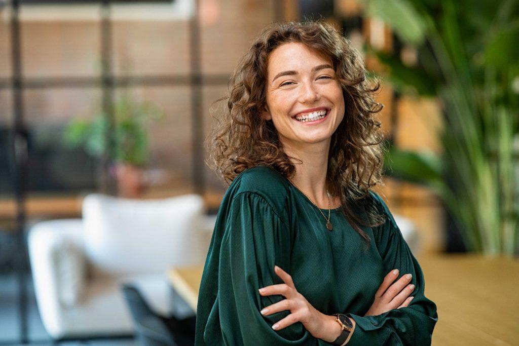 Woman in green shirt smiling with arms crossed.