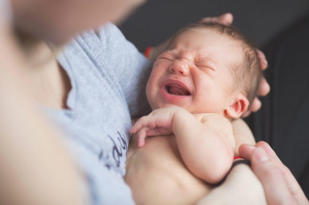 Mother holding crying newborn infant.