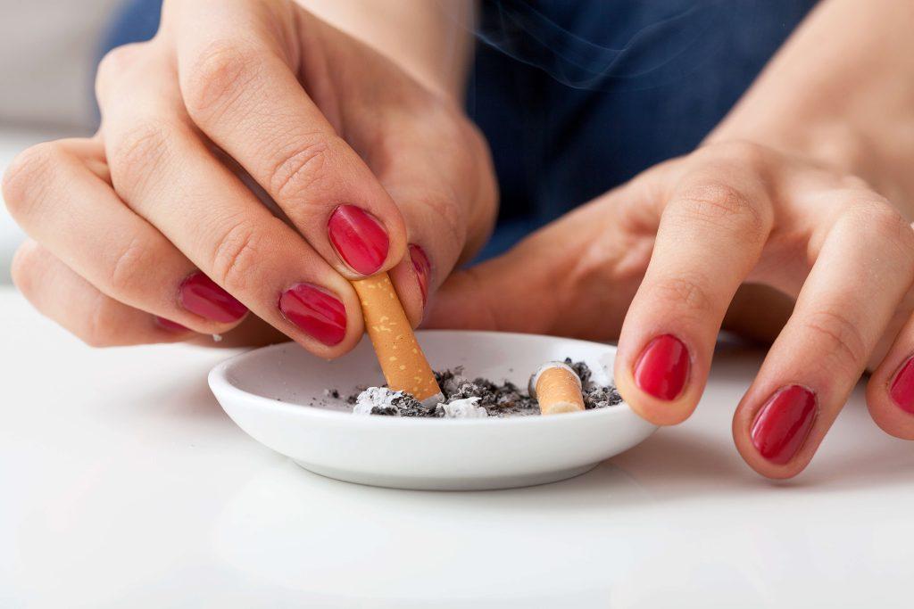 Hands putting out a cigarette in an ashtray.