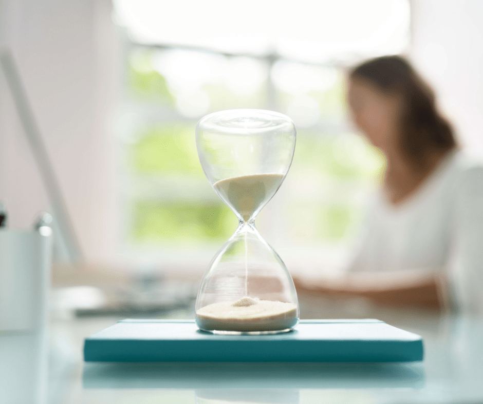 Woman blurred in background with hourglass in the foreground.