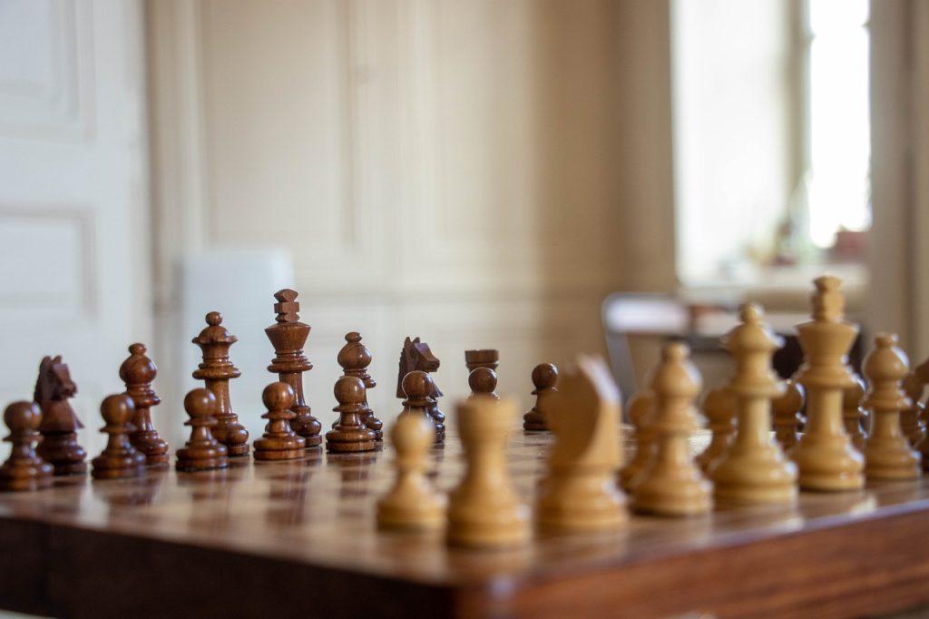 Wooden chess board with pieces set for a game.